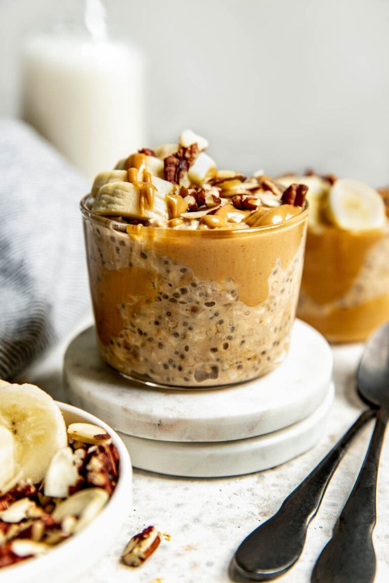 short glass jar filled with peanut butter overnight oats topped with banana slices and chopped walnuts.