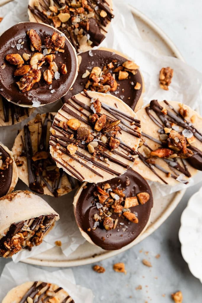 Several frozen protein peanut butter cups topped with chocolate and granola on a plate for serving.